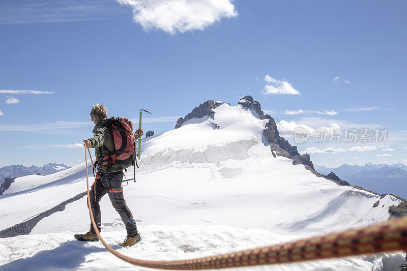 一位男性登山运动员到达了雪山的顶峰