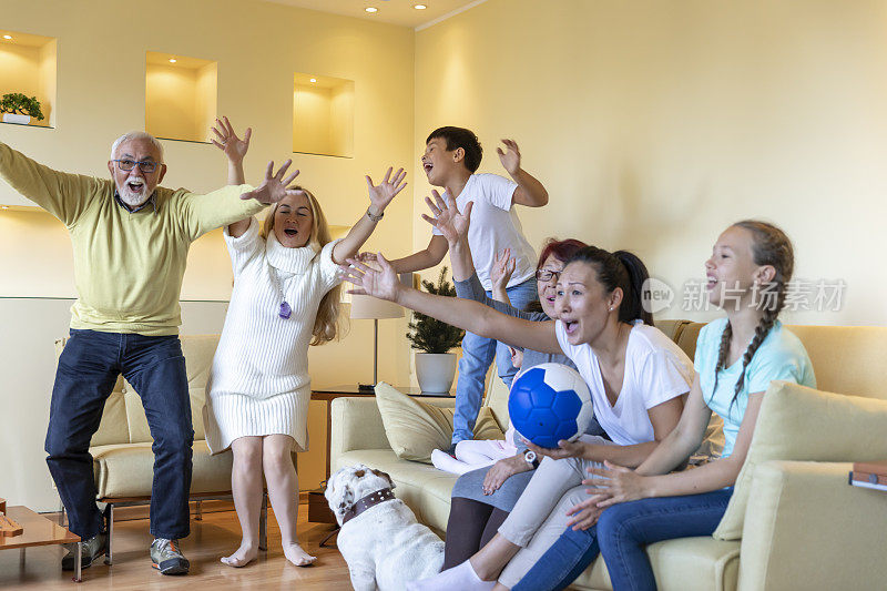 什么一个目标!一个欢呼的家庭正在一起看电视上的足球比赛。