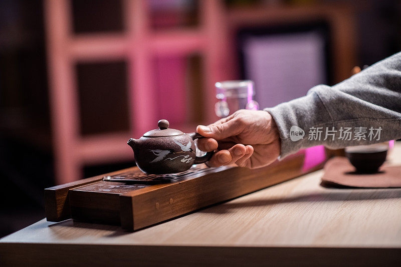 一个传统的陶瓷茶壶与热芳香的茶填充杯在一个木制托盘上的特写。模糊的背景