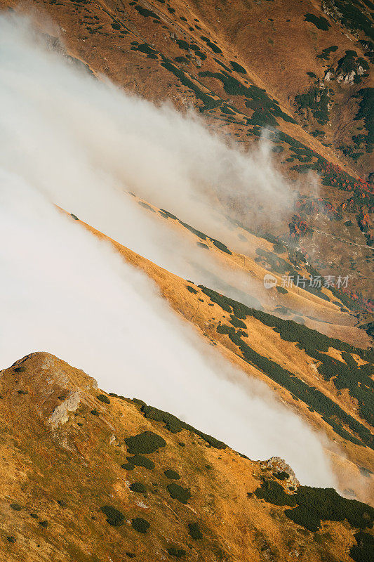 塔特拉山脉和阳光的秋景。云朵飘浮于山峰之上