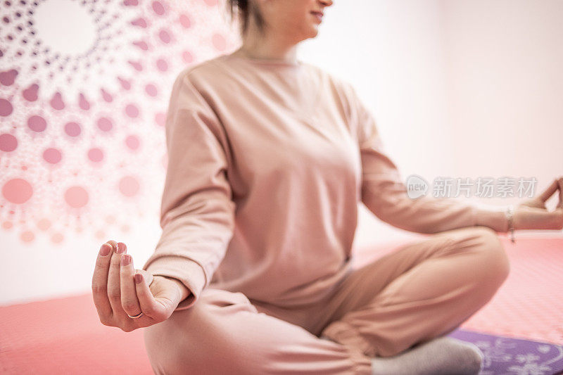 一位穿着粉红色运动服的年轻女子正在练习瑜伽