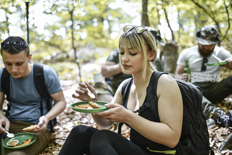 与徒步旅行团在森林里吃早餐的女性