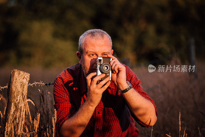 摄影师在大自然中使用老式胶片相机拍摄日落