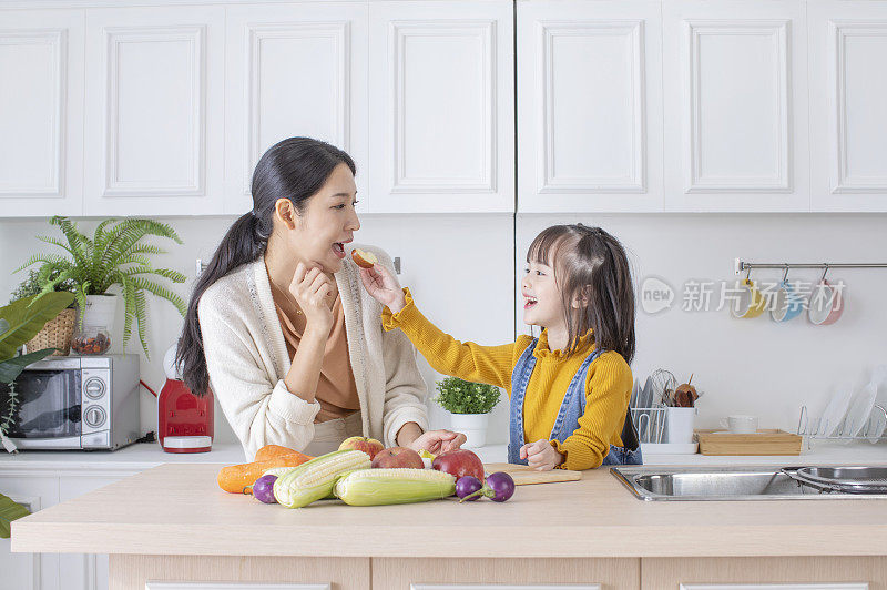美女妈妈和可爱女儿在厨房吃健康食物
