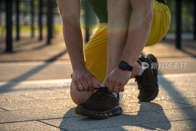 不可辨认的成年男子在运动场上系鞋带