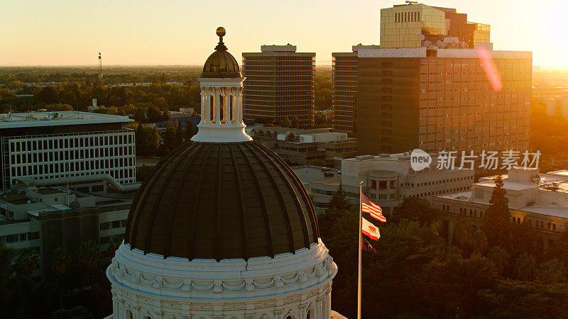 无人机拍摄的美国和加州国旗在日落时飞过州议会大厦