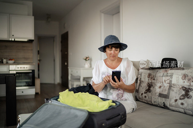 戴着帽子的女人的肖像使用电话和打包旅行