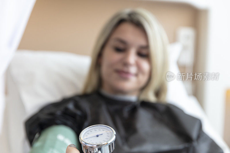 女护士在她的房间测量女病人的血压。