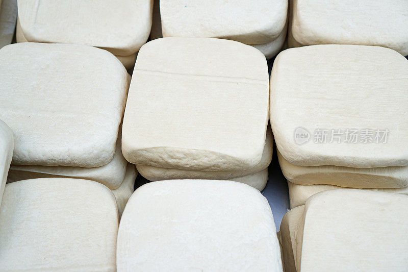 在一个新鲜的蔬菜市场，白色的豆腐块排列在桌子上。