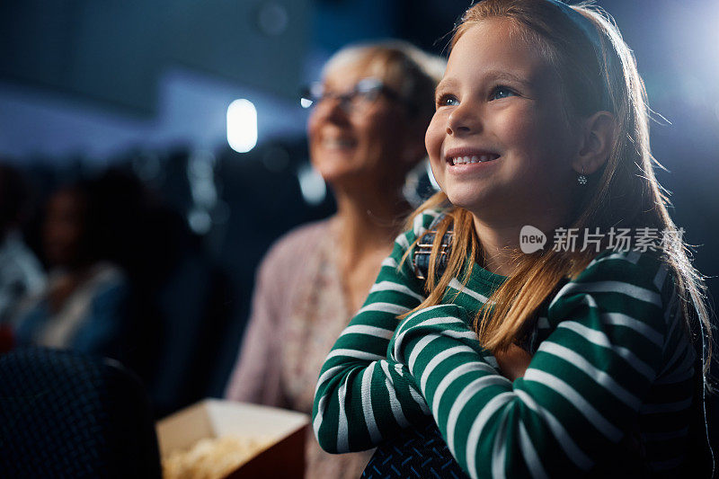 快乐的小女孩在电影院享受电影放映。