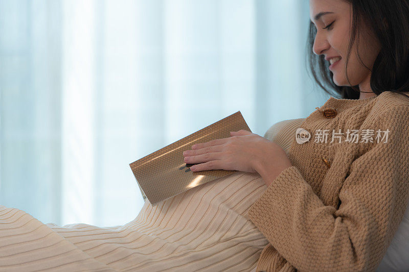 一位孕妇正在给她未出生的孩子读故事