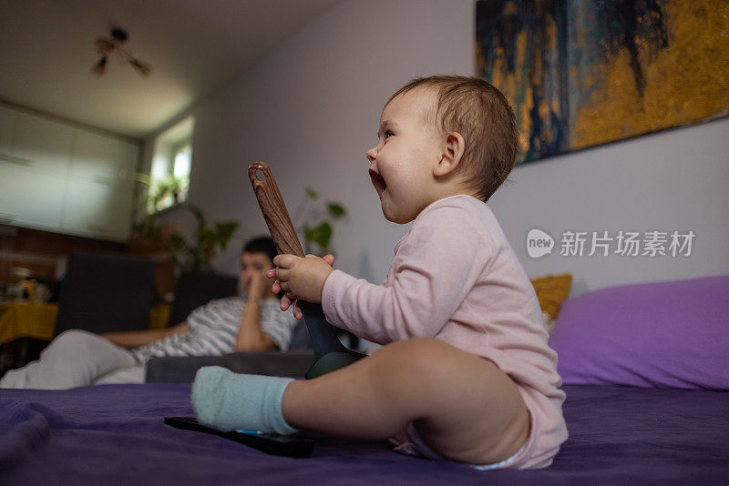 白人女婴坐在床上玩勺子