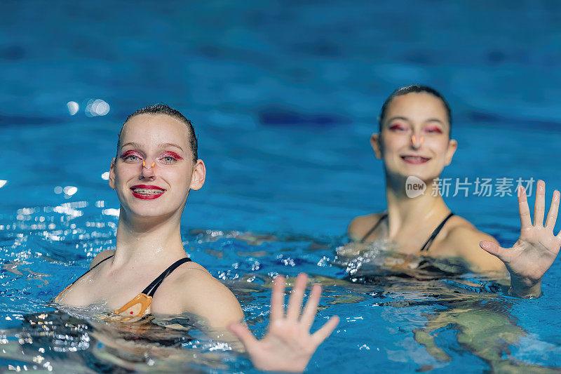 一个女子双人花样游泳表演，她们流畅的动作和同步的优雅创造了一个迷人的舞蹈池