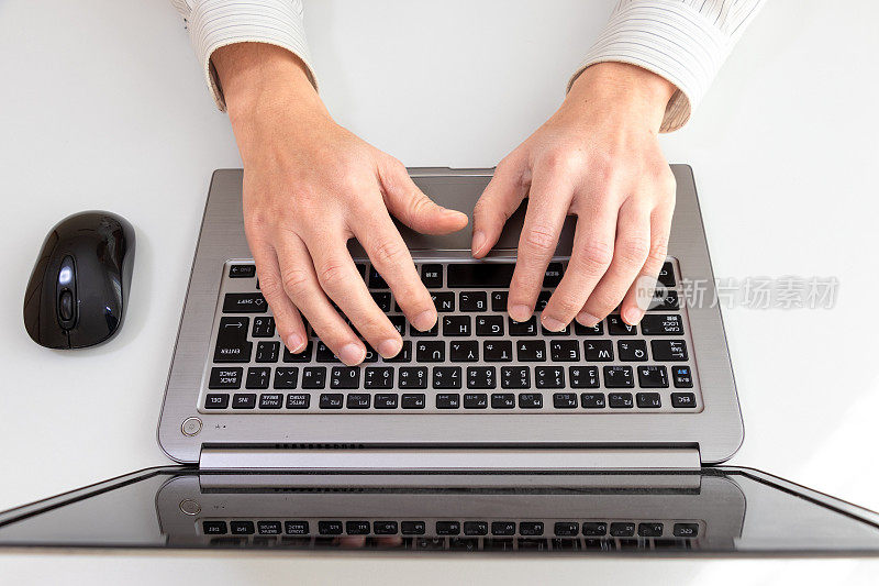 一个人的手敲击电脑键盘的俯视图