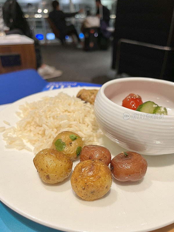 在机场的贵宾休息室享受豪华小吃熟食店:烤鸡、土豆、米饭和沙拉放在盘子里。