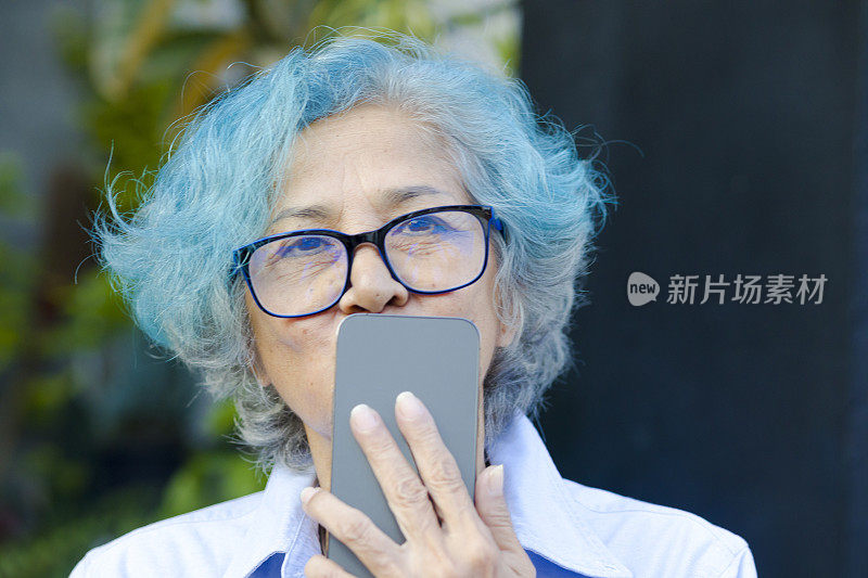 开心的泰国蓝发老女人亲吻手机