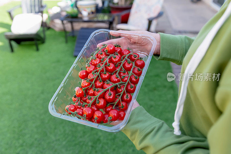 一个女人拿着一个装着西红柿的塑料容器