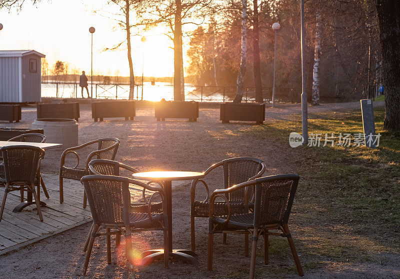 木阳台上空荡荡的夏日咖啡馆，黄昏的夕阳映在湖面上。