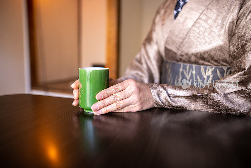 近距离的中年妇女抱着Yunomi，日本茶杯