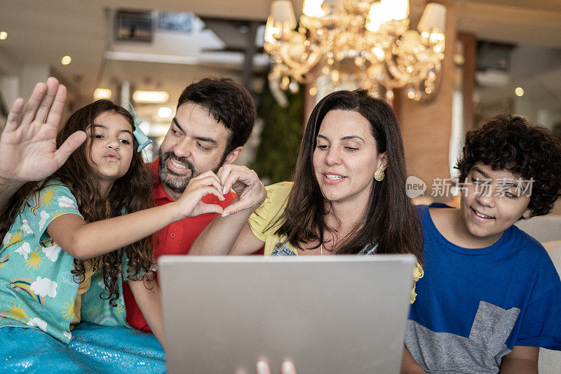 快乐的家庭在家里用笔记本电脑打视频电话