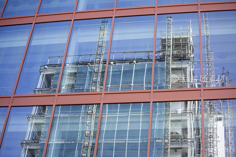 一座现代建筑上的脚手架反映在另一座建筑的窗户上