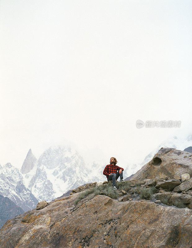 一名男子坐在巴基斯坦雪山的背景上