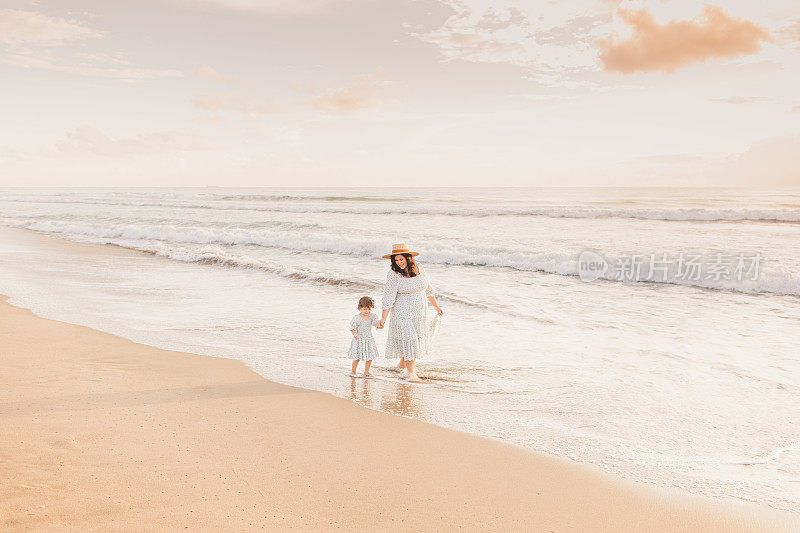 一个7个月的怀孕母亲和2岁的女儿在佛罗里达棕榈滩的金色日出期间一起享受时间