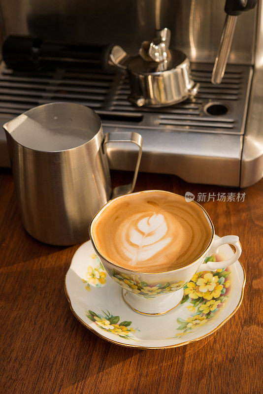 家庭咖啡师-自制的白色咖啡在古董骨瓷杯古董胡桃木桌子上