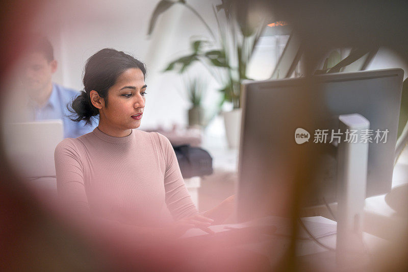 印度20多岁的年轻女性专注于她在公司办公室的工作
