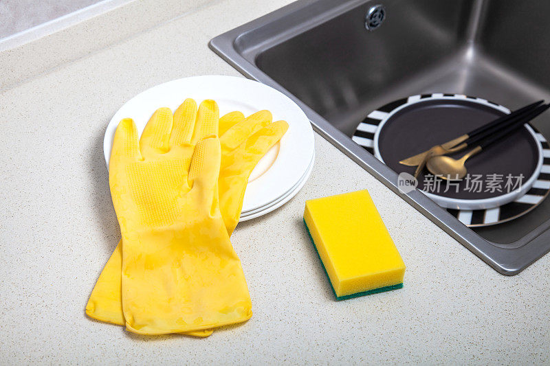 厨房水槽旁的黄色清洁海绵和橡胶手套