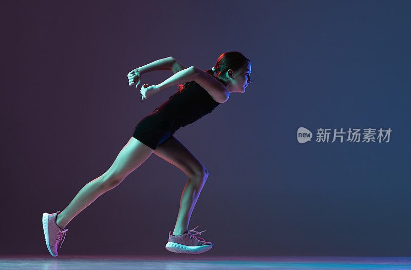 集中的女性运动员的全长肖像，女孩跑步，训练孤立的梯度蓝色紫色的背景在霓虹灯