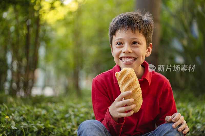 在绿色背景下吃面包的男孩