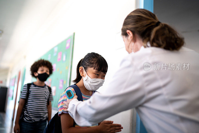 老师在学生进教室前，使用口罩在学生手上涂抹洗手液