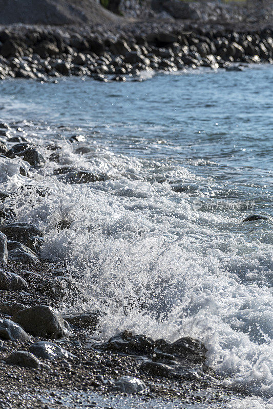 白色泡沫的波浪向海边的石头海岸靠近