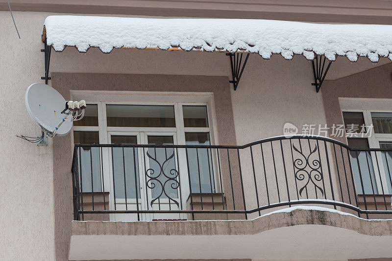 在下雪期间郊区住宅建筑的立面。房子的墙和阳台都被雪覆盖着