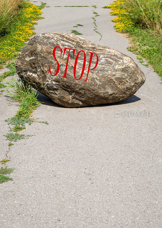 挂着红色“停止”标志的大石头挡住了路