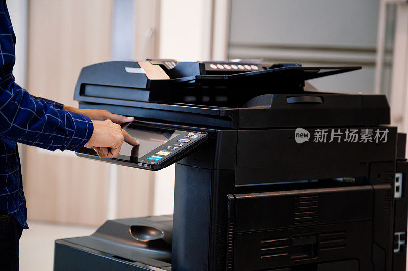 商务人士按下面板上的按钮，便可使用影印机或打印机在办公室打印或扫描文件。