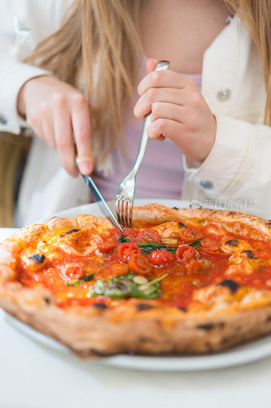 年轻女子享受素食披萨的画面