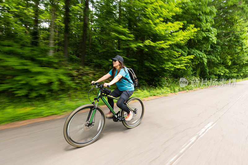 女子山地车骑穿过森林道路