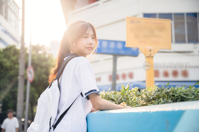 亚洲女孩在一个阳光明媚的日子放学回家