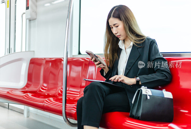 亚洲女商人在去办公室的火车上使用智能手机。