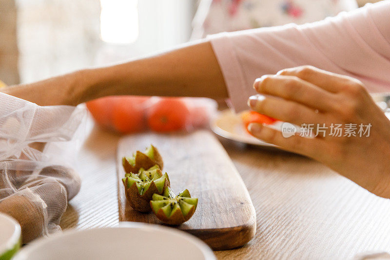 女子切猕猴桃成之字形，同时制作水果拼盘