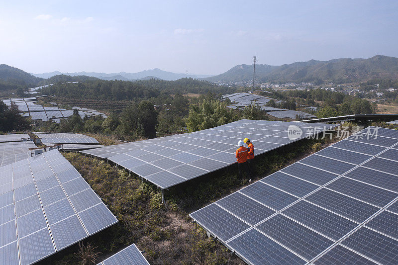 亚洲男性工程师在太阳能发电厂前讨论