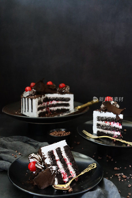 黑森林大门切片的图片，上面有莫雷罗樱桃，豪华的巧克力蛋糕上有奶油，上面覆盖着融化的巧克力，黑色背景，三层