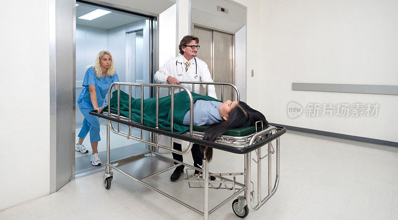 护理人员和护士把病人的床从电梯里推到医院的急诊室。