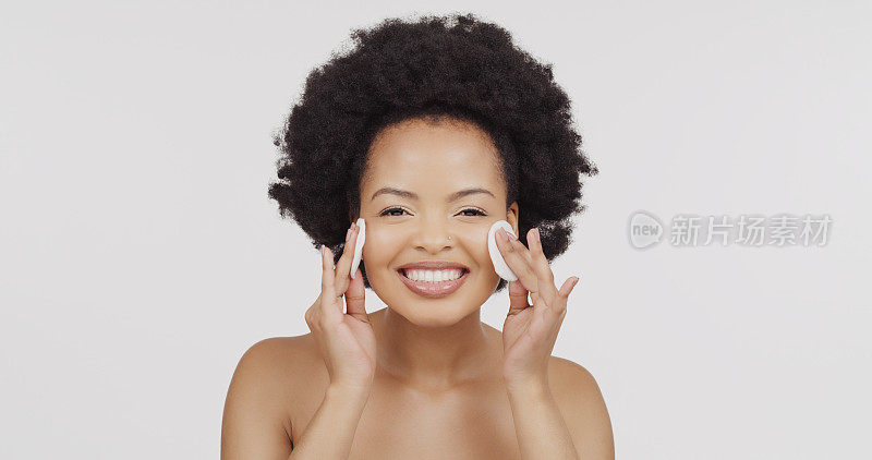 美容脸，肖像和非洲发型的黑人妇女用化妆，化妆品或护肤品的化妆棉清洁面部。皮肤病学，水疗沙龙和快乐的审美女孩孤立在灰色的背景