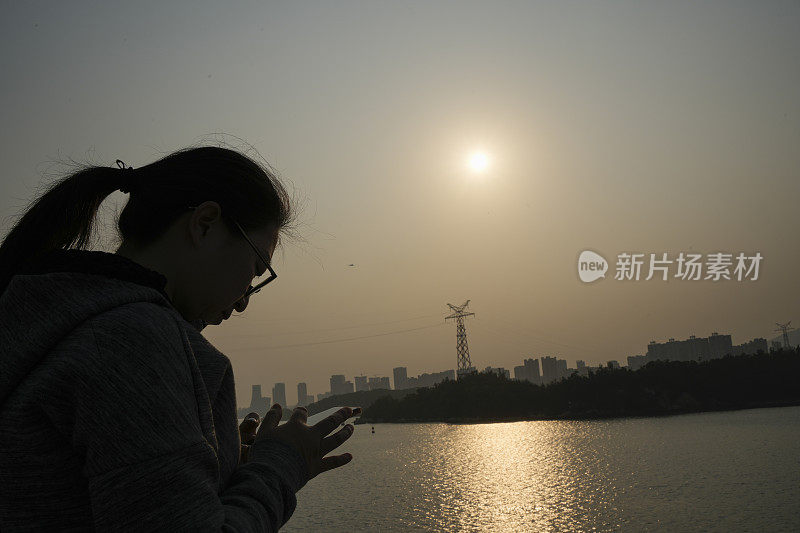 这位亚洲妇女正在用手机拍摄风景