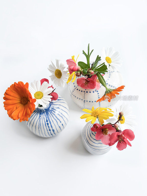 春天的花在小手工陶瓷花瓶与白色背景。