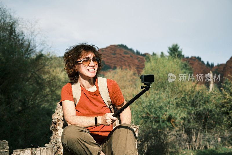 开朗的成熟女游客正在用视频记录她的登山经历