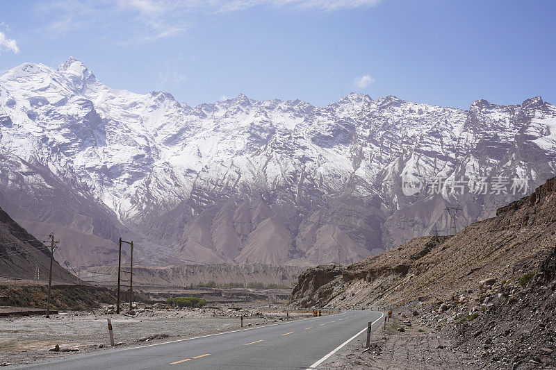 雪山背景公路位于帕米尔山区，空旷的柏油路配雪山